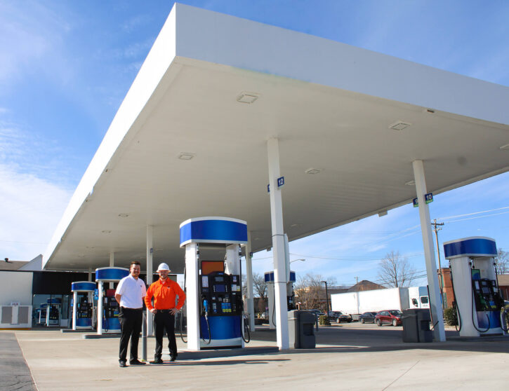 Two employees pose in front of convenience store build