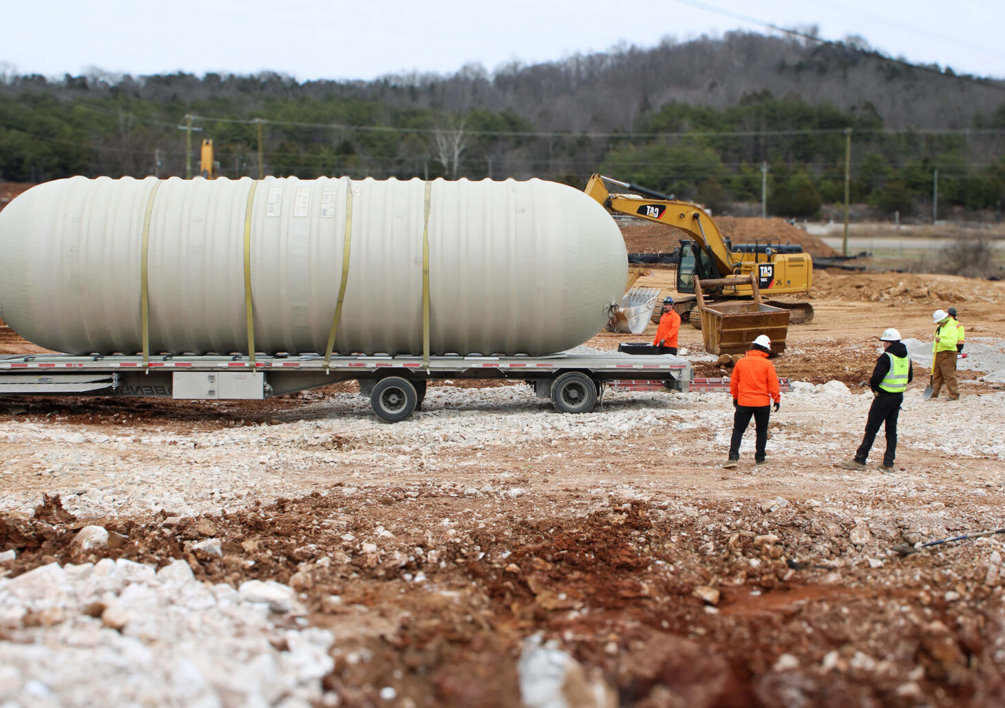 EPS Employees stand near large tank on-site