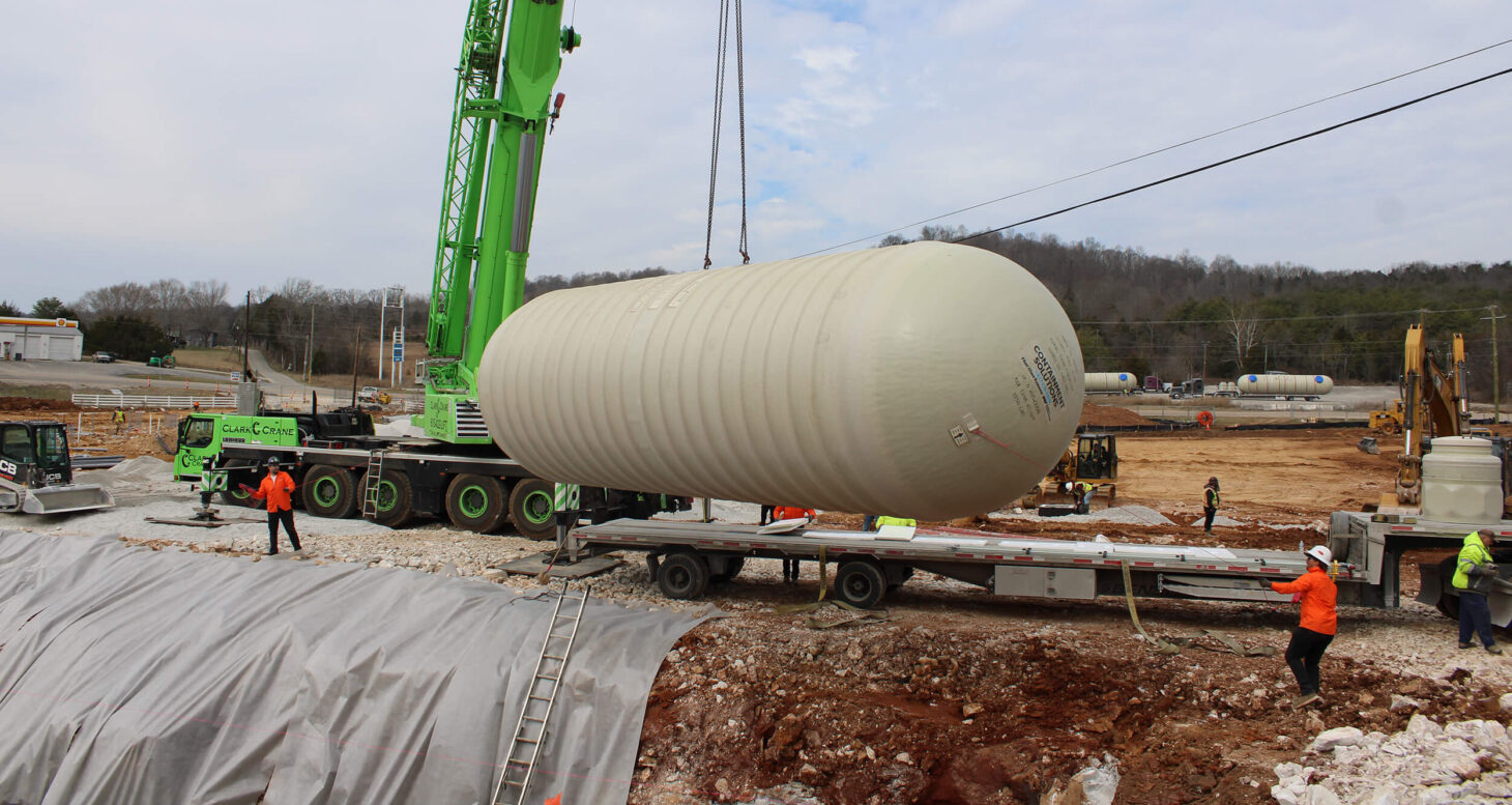 Image of crane lifting tank with employees